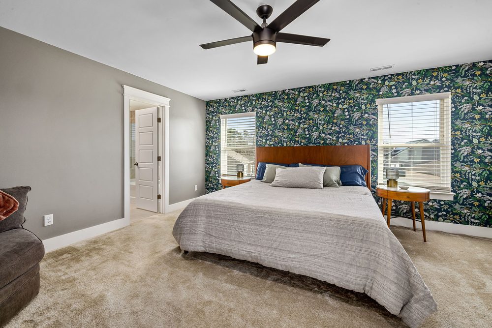 Bright bedroom with a navy botanical-floral wallpaper accent wall between two windows