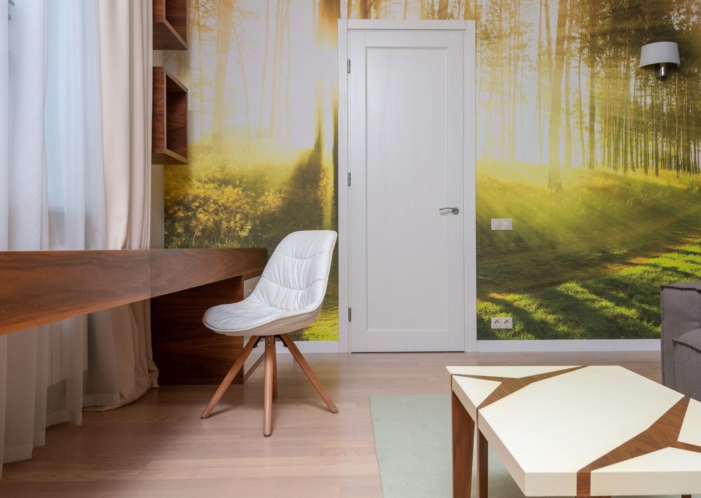Home office with a sunlit forest photo-mural wallpaper behind a walnut floating desk