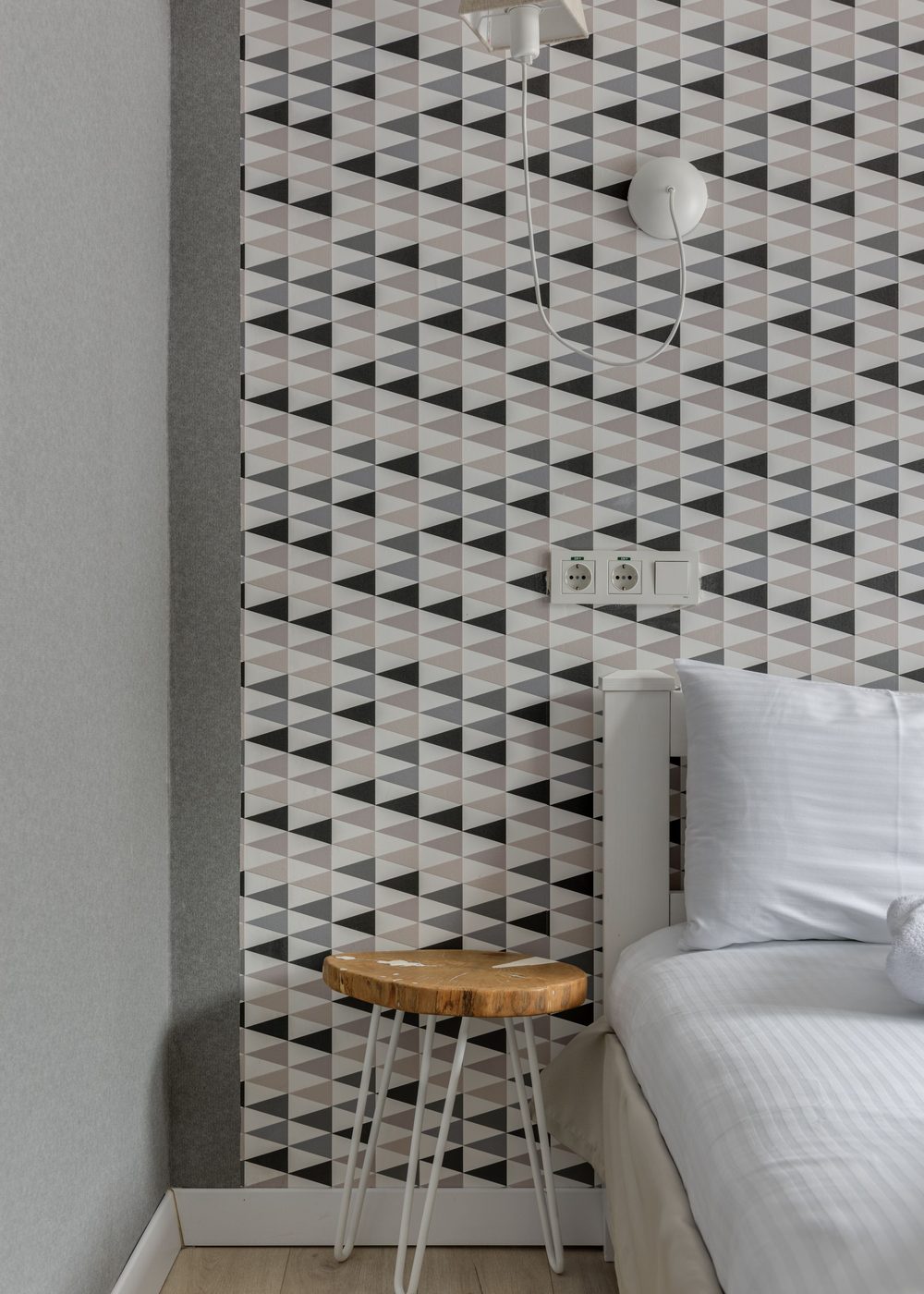 Contemporary bedroom feature wall in a black, grey and blush triangle geometric wallpaper