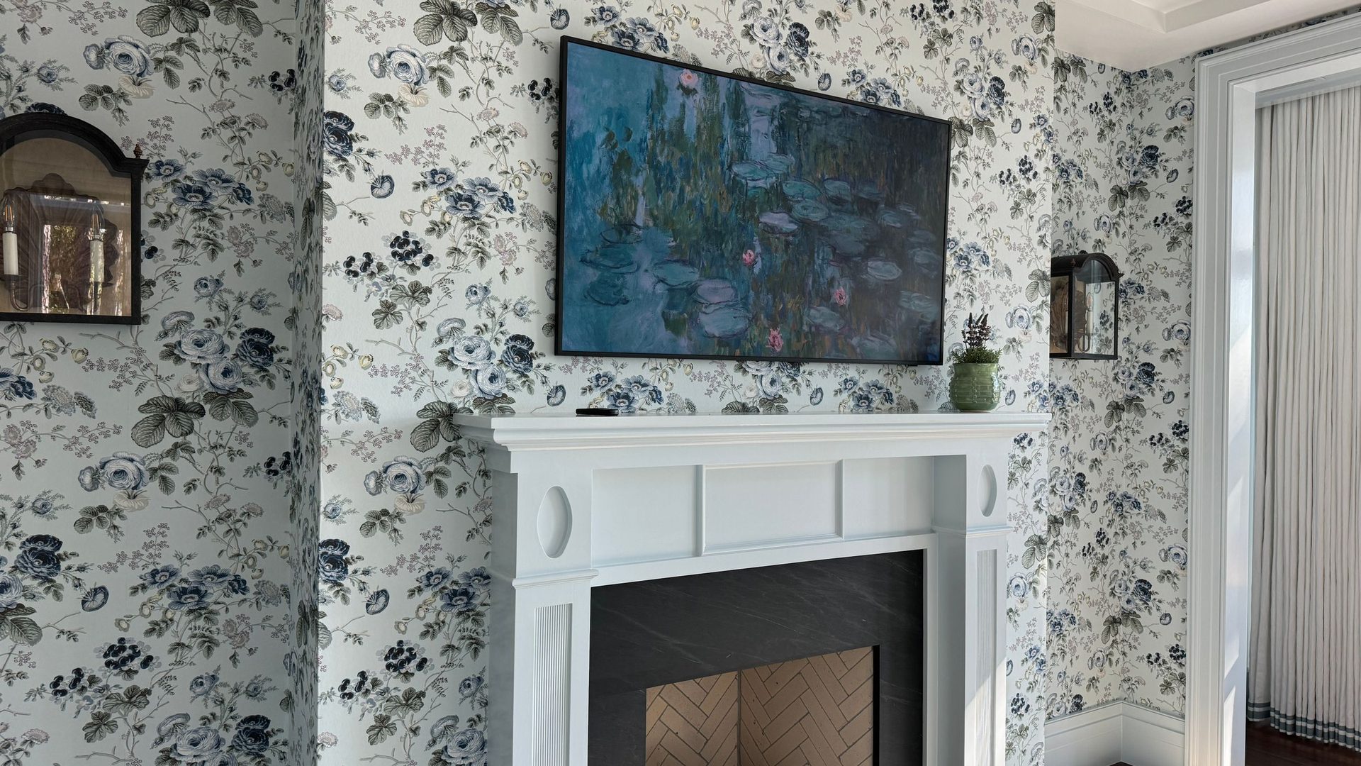 Elegant living room with blue and green floral wallpaper framing a white fireplace mantel